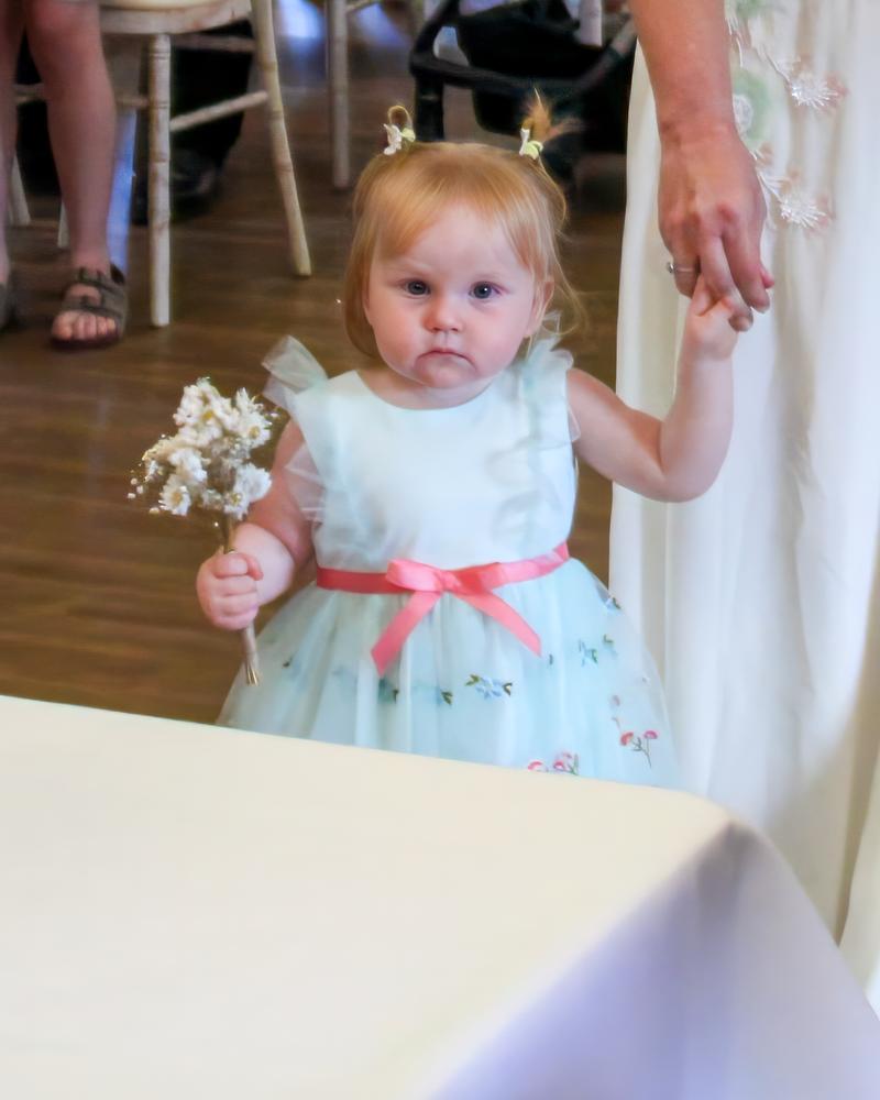 A tiny flower girl clutching her bouquet