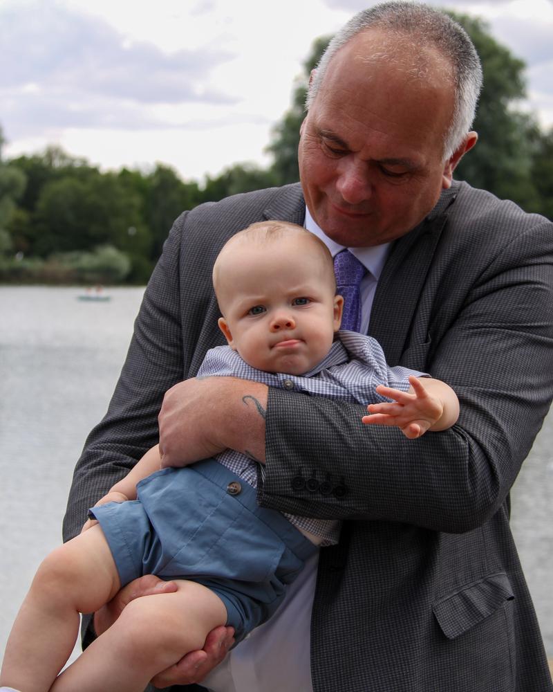 A grandfather holding a baby by the lake