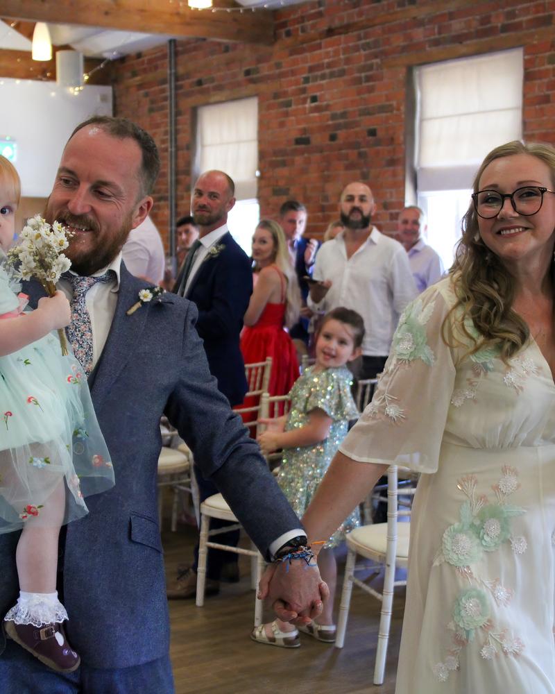 The newlyweds walking back down the aisle with their daughter