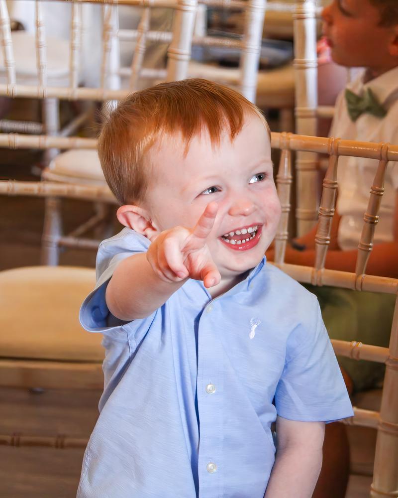 A young guest laughing and flashing a peace sign at the ceremony