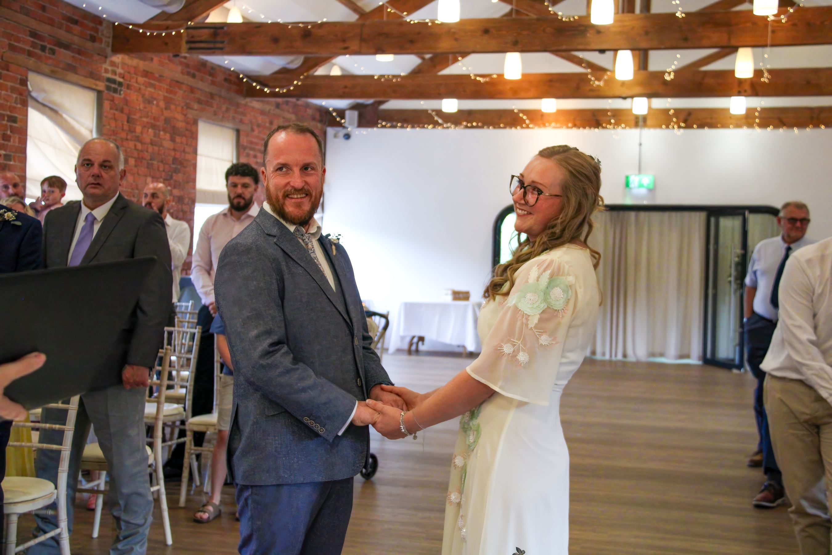 Bride and groom holding hands in a fairy-lit barn